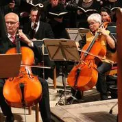 Zwei Musiker spielen Celli in einem Orchester.